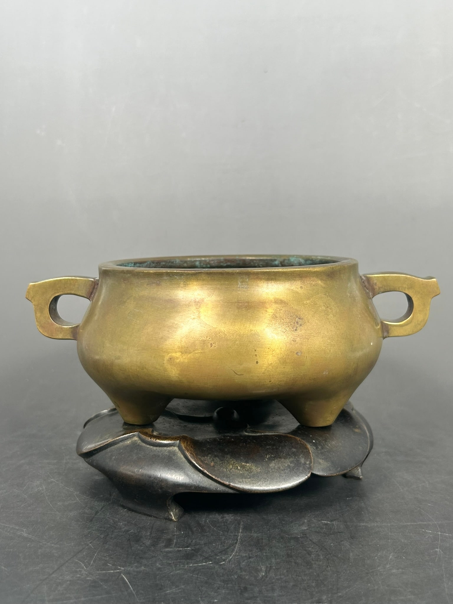A Chinese Bronze Tripod Censer: With a bronze base, apocryphal Xuande mark to the underside. 3.1/8 in. high, 8.1/2 in. wide for the censer.