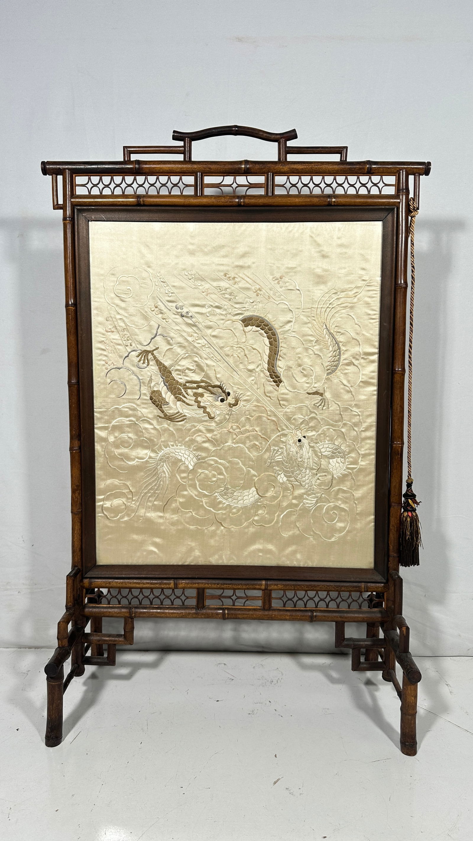 A Bamboo and Embroidered Panel Fire Screen: 40 in. high, 25.1/2 in. wide overall.