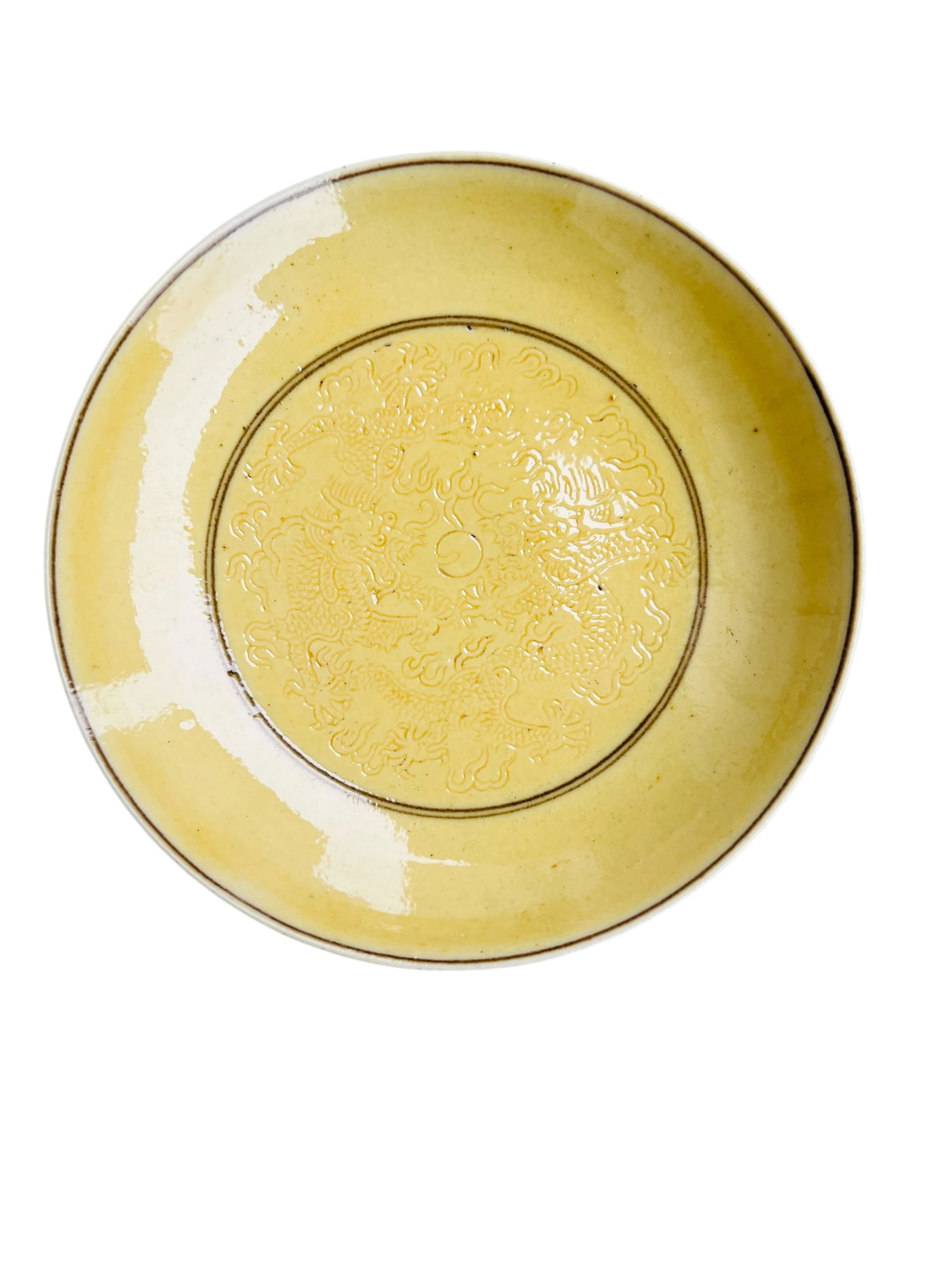 A Chinese Yellow Glazed Dragon Plate, Qing Dynasty: Chinese Qing Dynasty yellow-glazed plate, finely incised with twin dragons chasing a flaming pearl beneath the glaze.Diameter: 4 1/2 inches.Condition: good.
