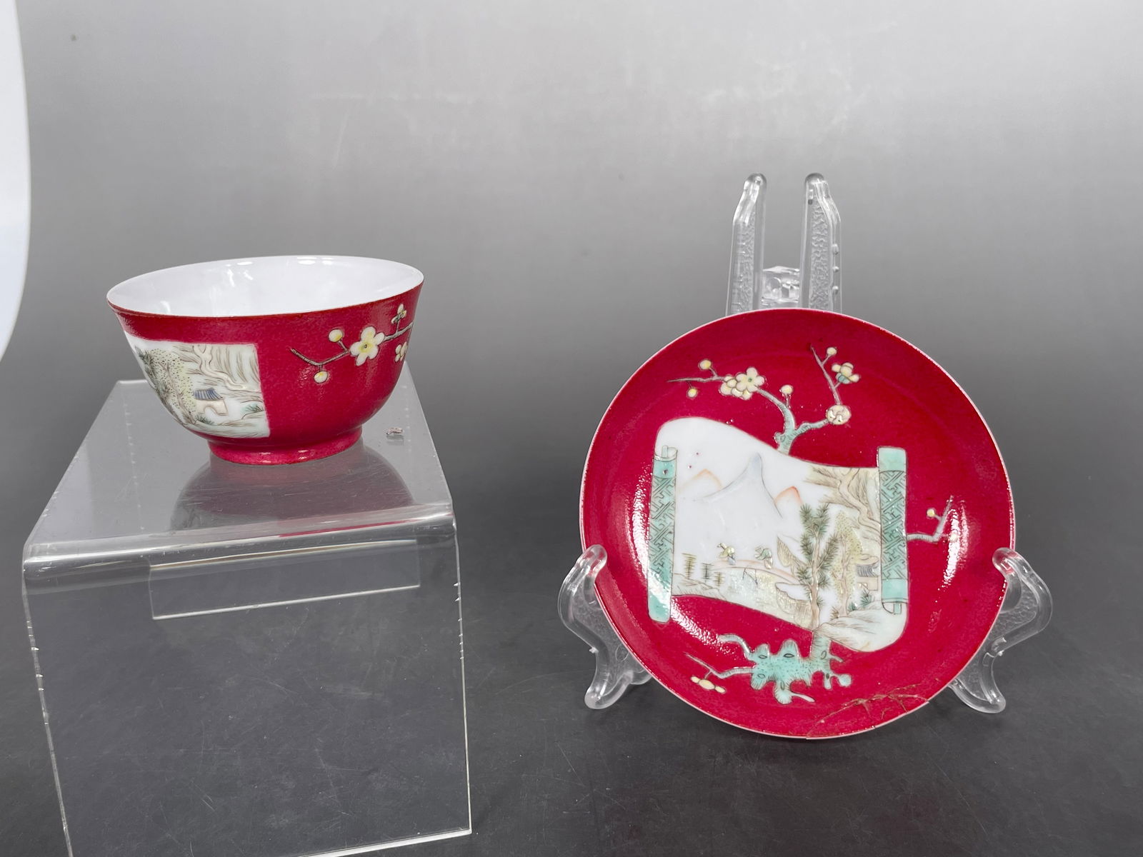 A Chinese Coral Red Famille Rose Cup and Saucer Set, Qing Dynasty: Chinese Qing Dynasty coral-red ground famille rose cup and saucer set, decorated with reserve panels.Saucer diameter: 4 1/4 inches; cup diameter: 2 3/4 inches. H: 1 1/2 inches.Condition: the cup in