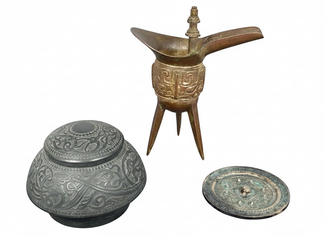 A Group of three Chinese Archaistic Bronze Objects: Comprising a bronze inkwell, 3.3/4 in. high, 4.3/4 in. wide; a wine vessel jue, 7.1/8 in. high, 5.3/4 in. wide; and a small mirror, 3.3/4 in. diam.