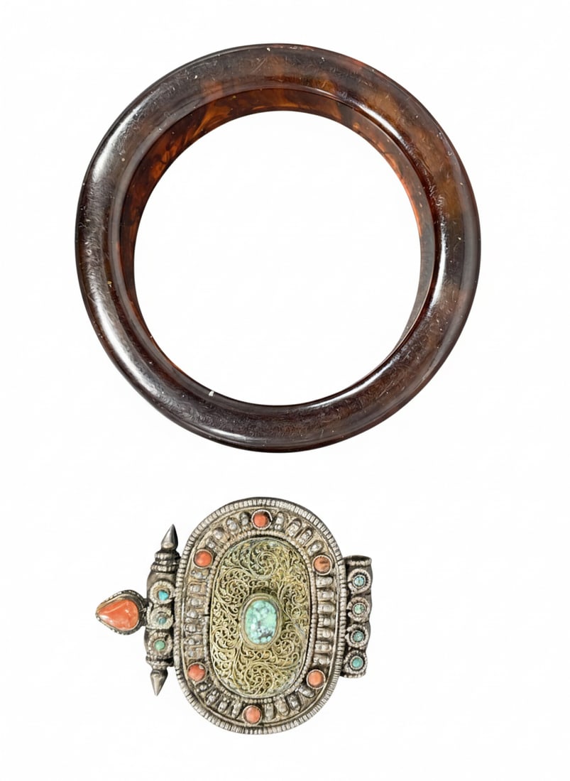 An Amber Bangle and a Tibetan Amulet: The bangle measures 3.1/4 in. diam., 1 in. thick; the amulet measures 2.3/8 in. high, 2 in. wide.
