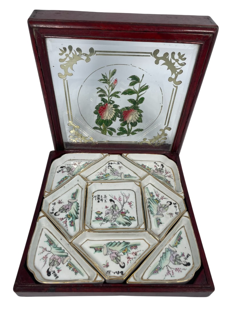A Chinese Set of Qianjiang Enameled Sweat Meat Dishes: Comprising nine compartments featuring ladies. The central dish measures 3.7/8 in. square. Wood/glass box, 3 in. high, 11 in. square.