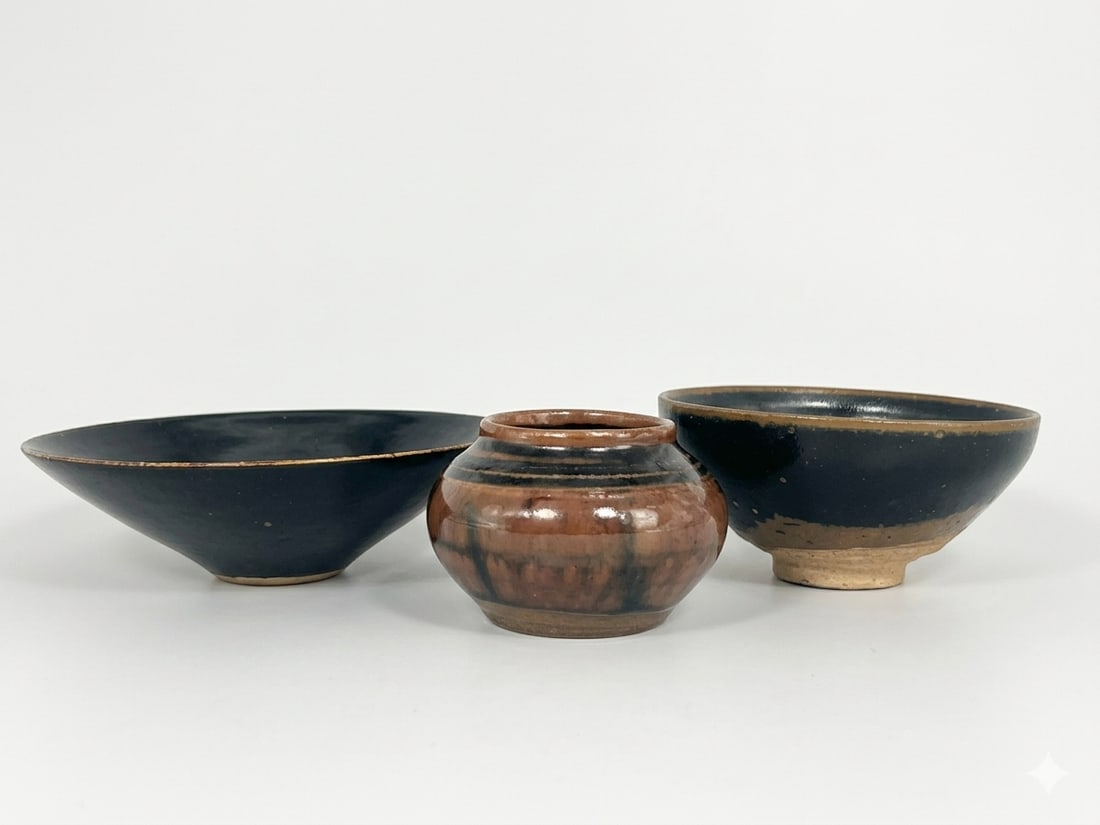 A Group of Three Chinese Porcelain Ware: Comprising a Jianzhou-style leaf-decorated conical tea bowl, 1.3/4 in. high, 5.5/8 in. diam.; a black-glazed tea bowl, 2.1/8 in. high, 4.1/4 in. diam.; and and a small brown-glazed jar, 2.1/8 in. high