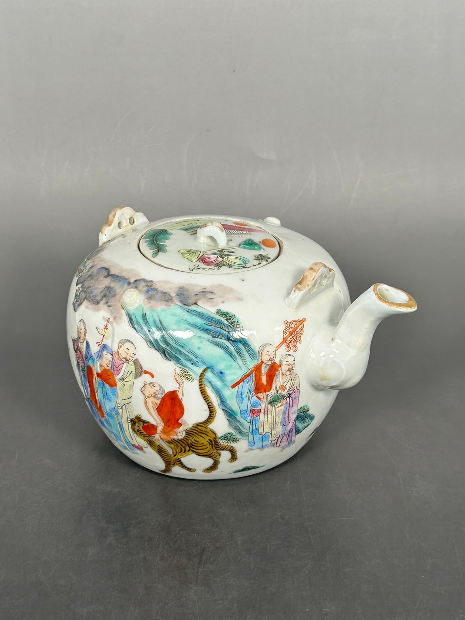 A Chinese Famille Rose 'Buddhist Monks' Porcelain Teapot and Cover, Daoguang Mark: A Daoguang mark to the underside. 5 in. high, 8 in. wide.