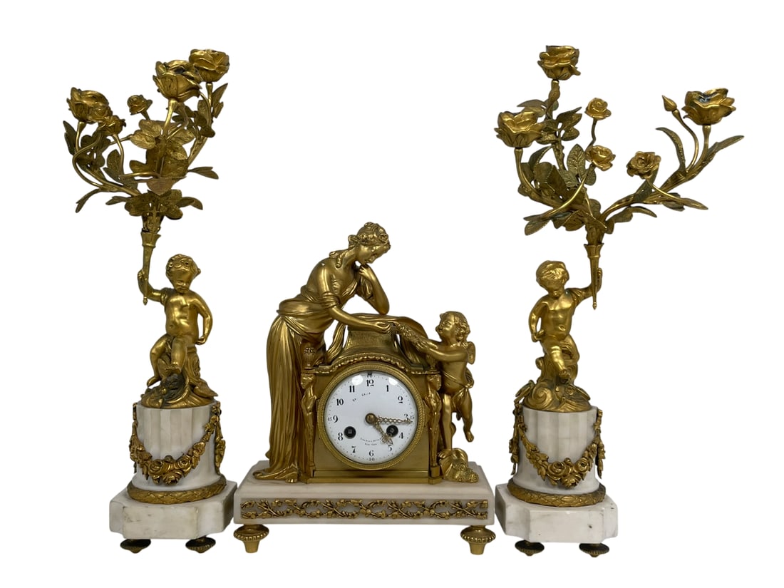 A Pair of Gilt-Bronze Candelabra and a Gilt-Bronze Mantel Clock: The pair of candelabra measures 17 in. high, 7.1/2 in. wide; the clock measures 10.3/4 in. high, 8.1/2 in. wide.