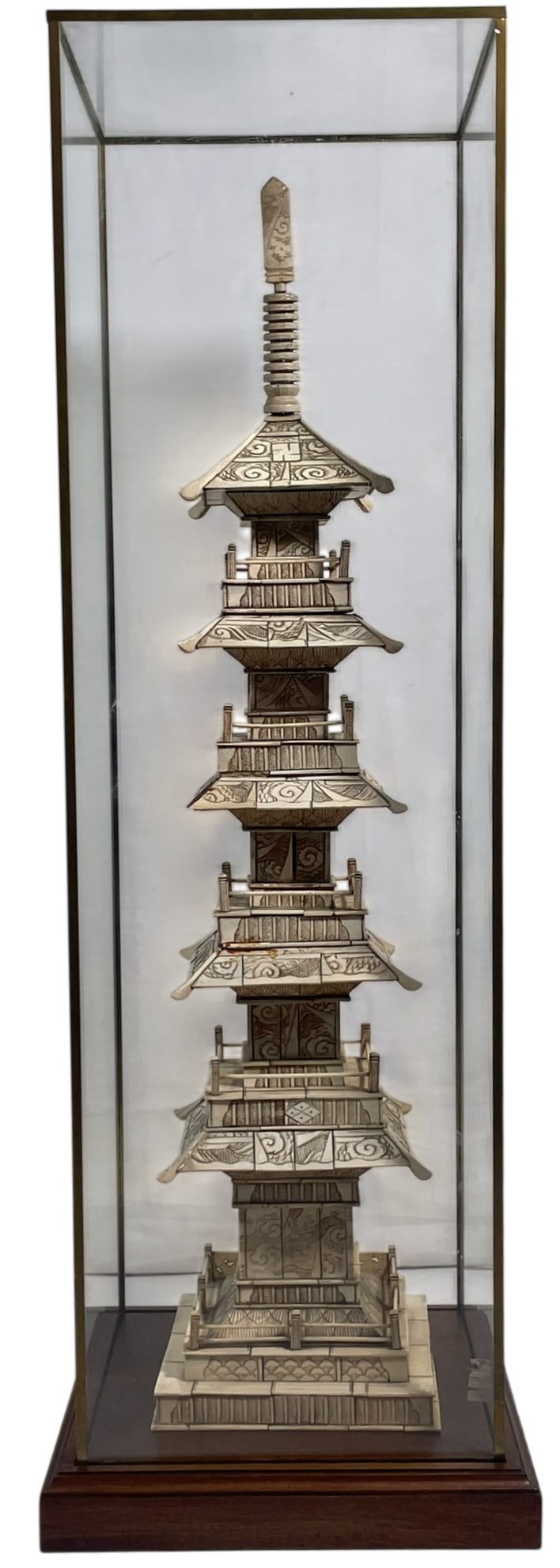 A Japanese Carved Bone Pagoda, Early 20th Century: Of five tiers with a buddha shrine to the base. From a Westchester home. With bronze/glass case and wood base. 30.1/4 in. high, 7 in. wide for the pagoda, 34.1/2 in. high, 11.1/2 in. square for the ca