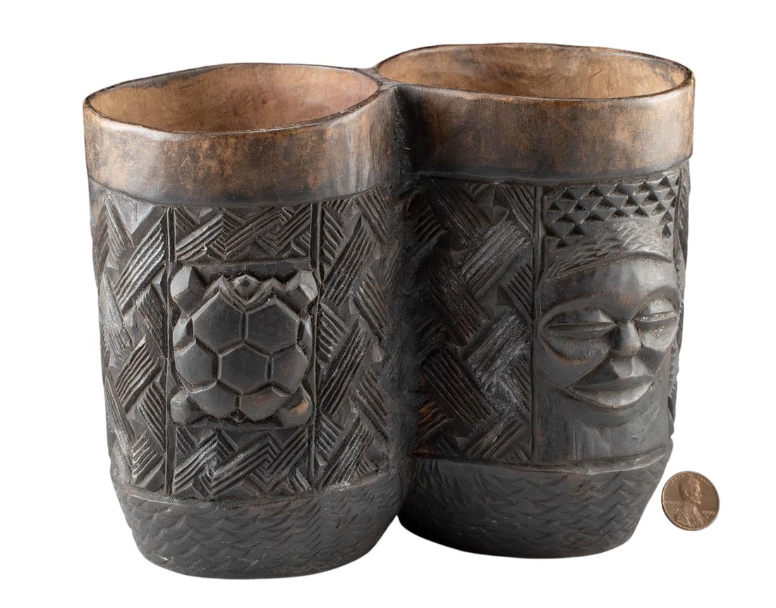 An African Kuba Wood Palm Wine Cup, Conjoined Vessels, Mid-20th century: Central Africa, Democratic Republic of the Congo, Kuba culture, circa mid-20th century. A finely hand-carved wooden palm wine cup of double-vessel form, featuring a handle embellished with an anthropo