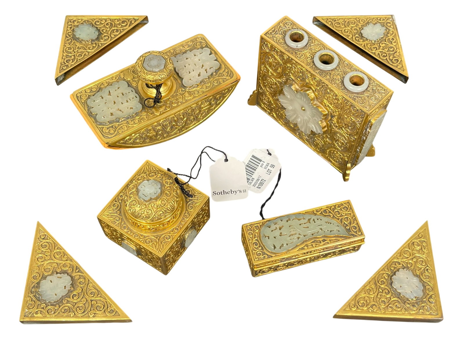 Sotheby's Provenance: An Eight-Piece Chinese Gilt-Metal and Jade-Inlaid Assembled Desk Set, 20th: Jade plaques: 17th - 19th century, comprising an inkwell, a pen holder, a stamp box, a hand blotter and four blotter corners. The tallest pen holder measures 3.3/4 in. high, 4.3/4 in. wide. Provenance