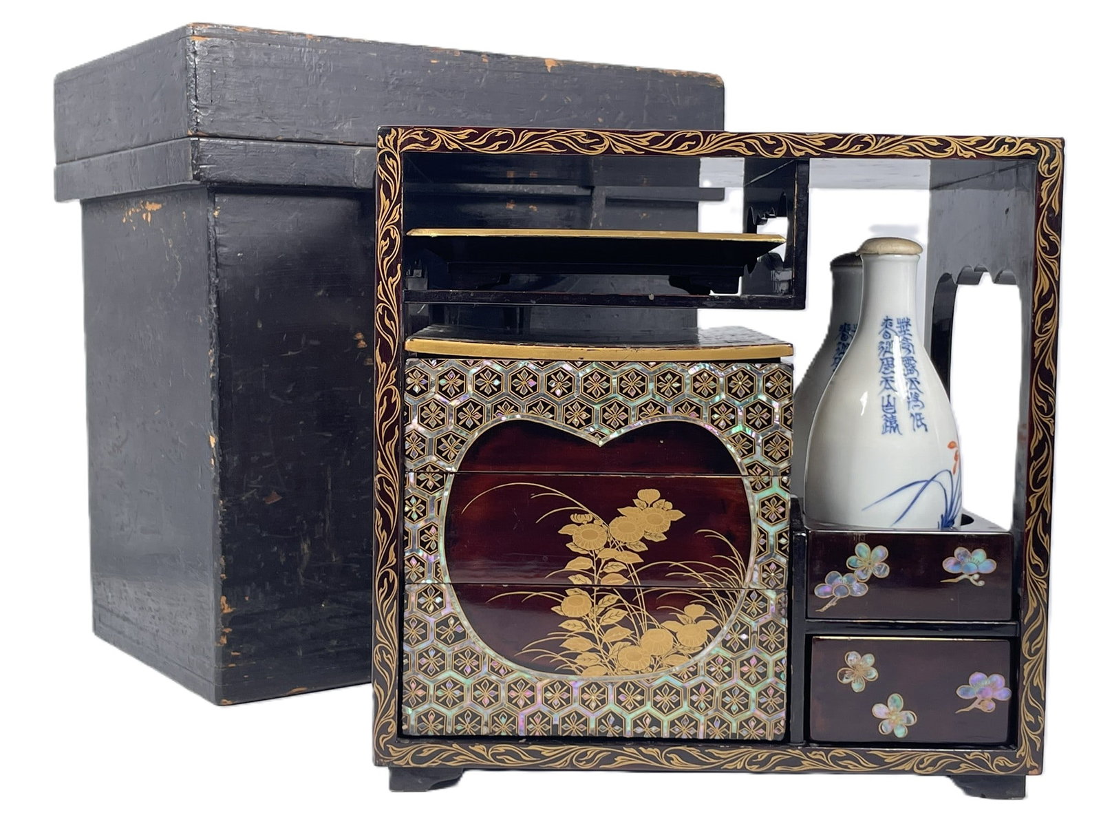 A Japanese Lacquer Sage-Jubako Picnic Set: The set includes a rectangular carrying frame (with a metal handle), a multi-tiered food box (jubako), and ceramic tokkuri (sake bottles) 12.1/2 in. high, 12.1/2 in. wide, 8.1/2 in. deep overall.