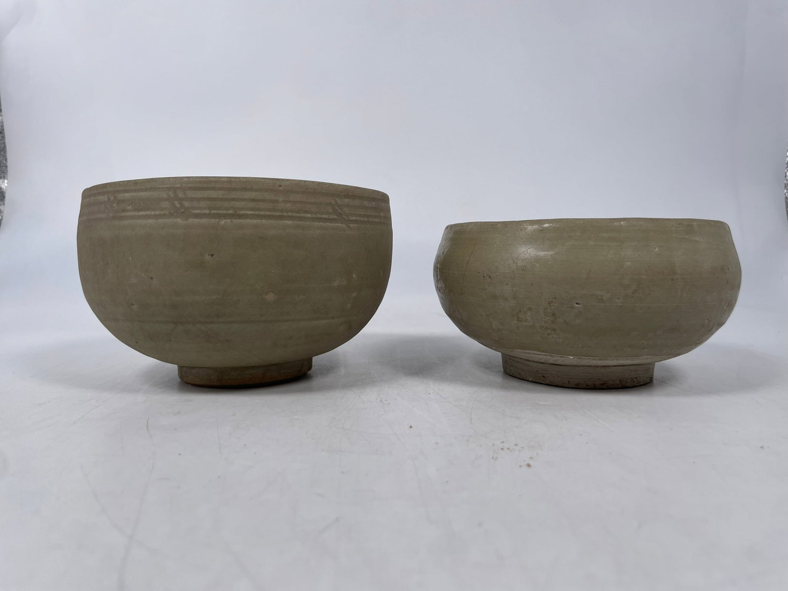 Two Chinese Celadon-Glazed Porcelain Deep Bowls, Song Dynasty: The taller one measures 3.3/8 in. high, 5.1/2 in. diam.; the other one measures 2.3/4 in. high, 5.1/4 in. diam. Provenance: From the renowned John Allen Tabor Collection. John Tabor (1917?1991), a U.S