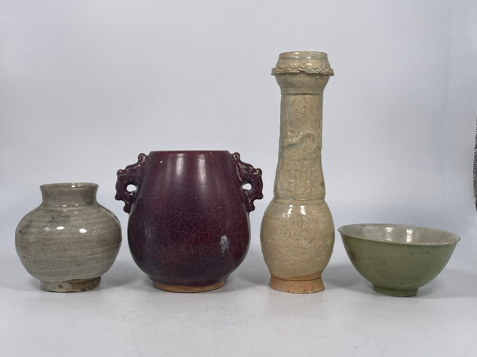 A Group of Four Chinese Porcelain Ware: Comprising a celadon glazed funerary jar, probably Song dynasty, 10.1/2 in. high, 3.1/4 in. wide; a flambe-glazed hu-form vase, 6.1/4 in. high, 6.1/2 in. wide; a jarlet, Ming dynasty, 4.5/8 in. high, 
