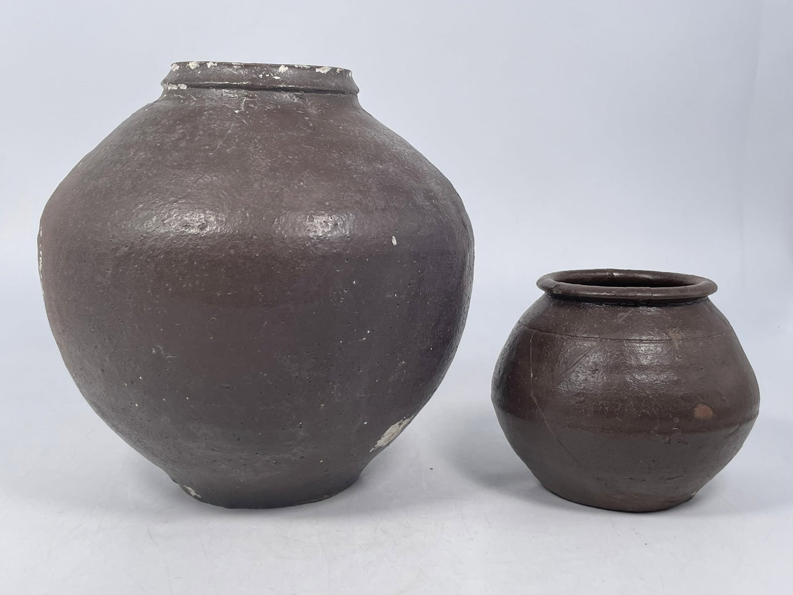 Two Korean Brown-Glazed Jars: The larger one measures 9 in. high, 8.3/4 in. wide; the smaller one measures 4.3/4 in. high, 5.1/4 in. wide. A Private Collection of a Retiring University Professor.