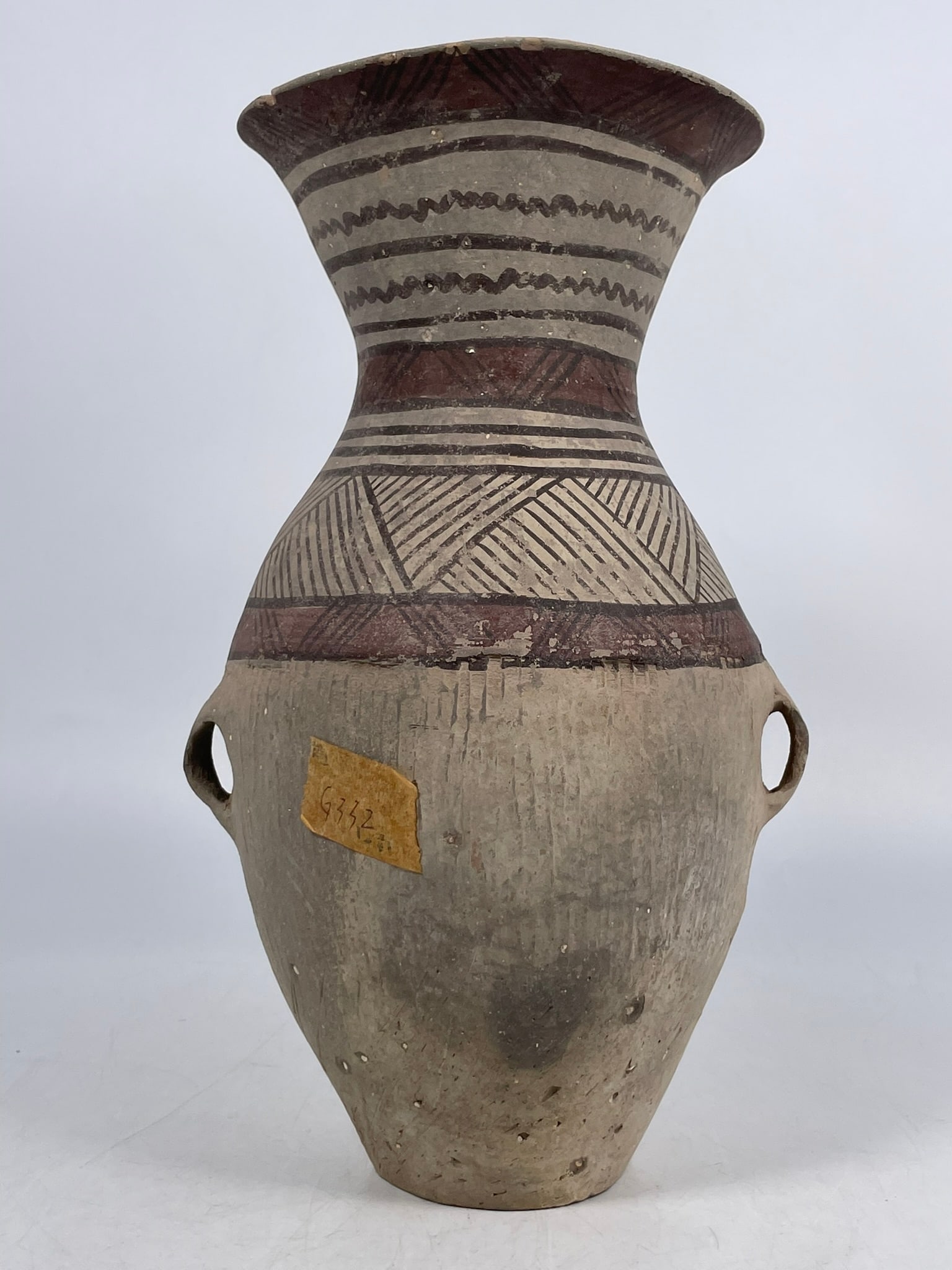 A Chinese Painted Pottery Vase, Neolithic Period, Majiayao Culture, 3rd Millennium BC: Features geometric patterns, including zigzags, horizontal bands, and crosshatching, painted in black and red pigments over the clay body. 12 in. high, 7 in. wide. A Private Collection of a Retiring