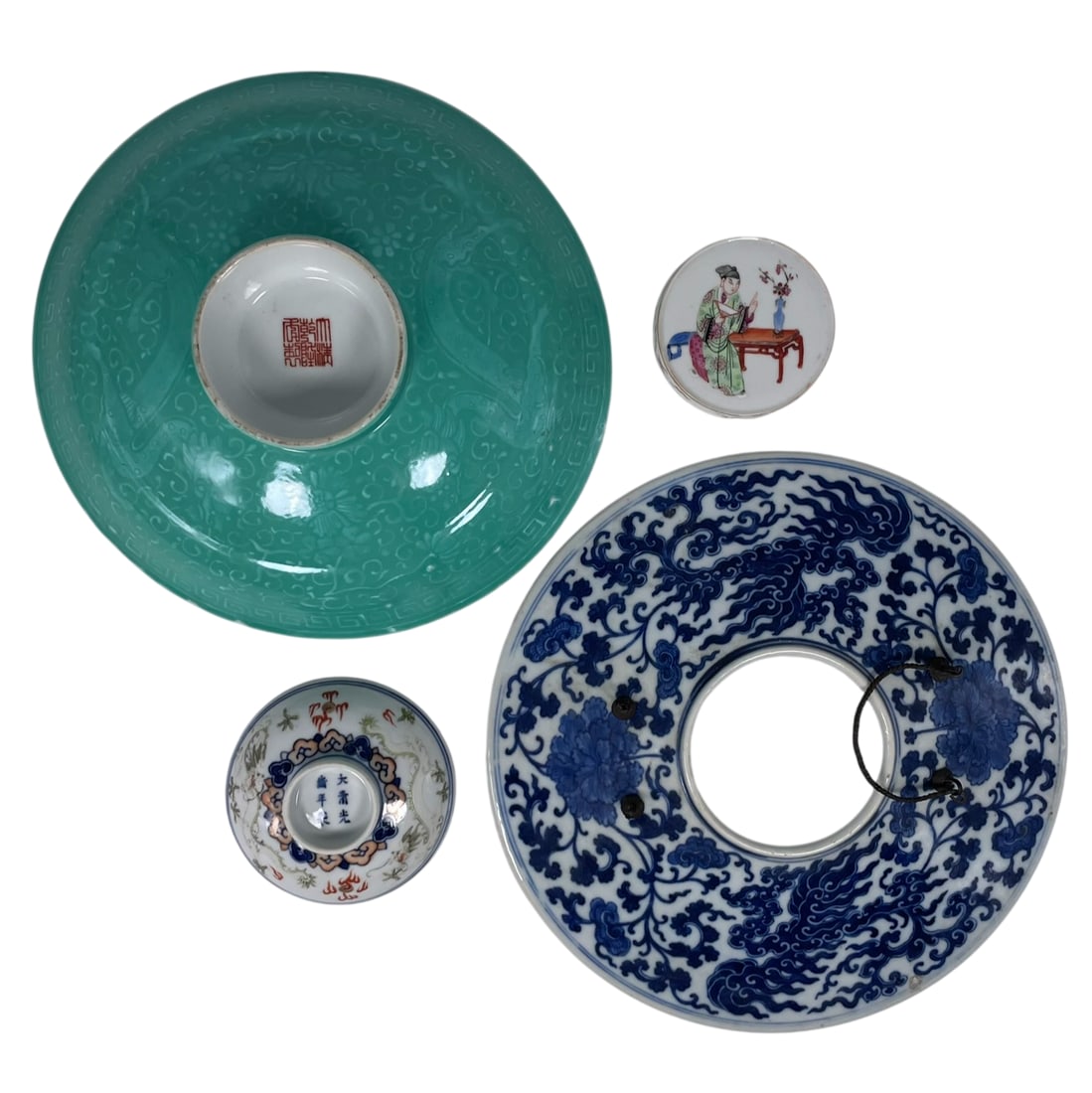 A Group of Four Chinese Porcelain Covers: Comprising a blue and white cover, 9.3/4 in. diam.; a green-glazed cover, apocryphal Qianlong mark, 3 in. high, 8.3/4 in. diam.; a tea cup cover, Guangxu mark, 3.3/4 in. diam.; and a famille rose circ