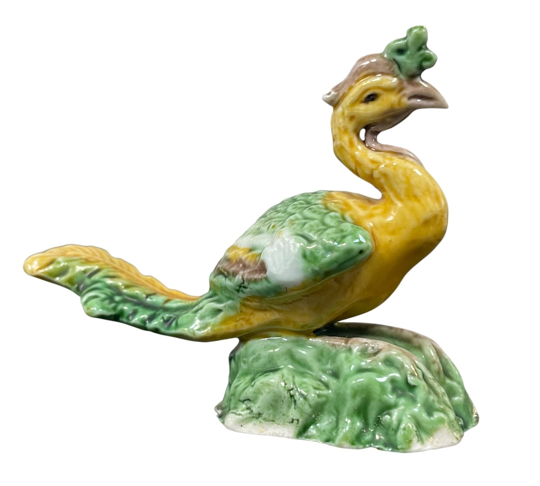 A Chinese Sancai-Glazed Figure of Phoenix, Late Qing Dynasty/Republic Period: A finely modeled Chinese miniature sancai-glazed ceramic figure of a fenghuang (phoenix) standing atop a rugged rocky outcrop, executed in the traditional sancai ("three-color") palette of vibrant yel