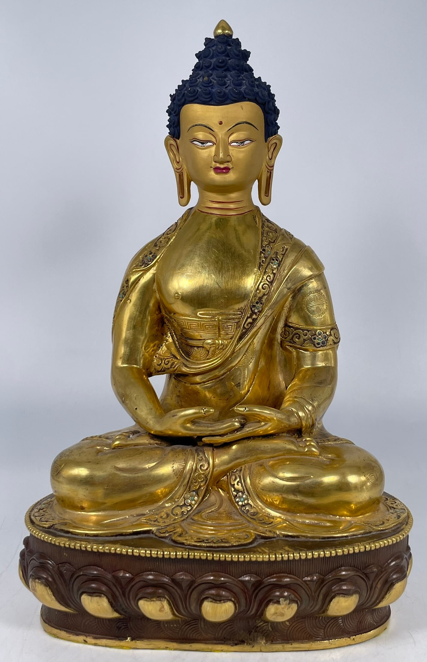 A Tibetan Gilt-Bronze Figure of Amitabha Buddha: Great quality, seated in the lotus position with hands in the Dhyana mudra on a embossed lotus pedestal, with a Tibetan seal underneath, covered by the protective cloth. 14 in. high, 8.3/4 in. wide.