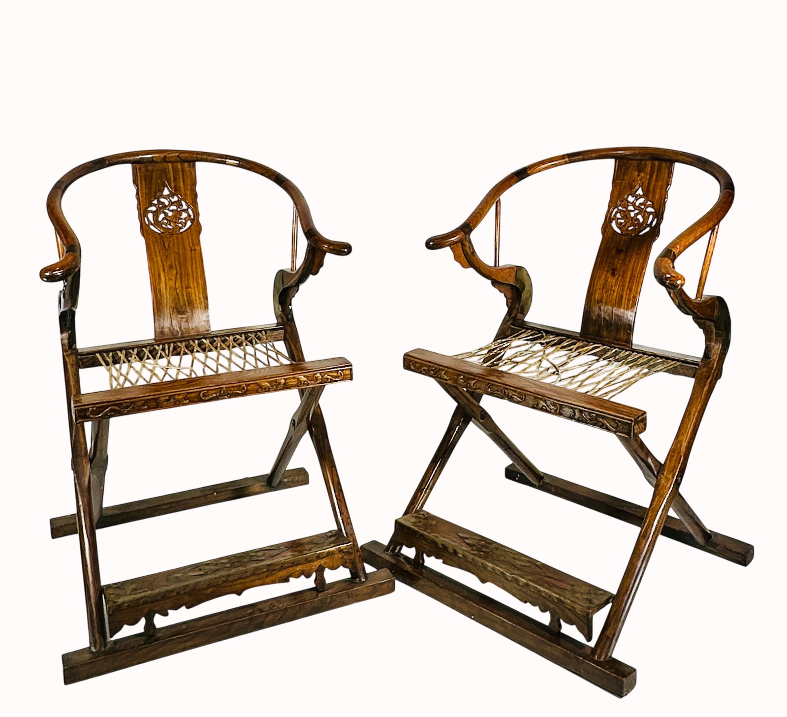 A Pair of Chinese Wood Folding Chair: The curved crest rail ends in out-swept hooks and is supported by a S-shaped back splat, which features a pierced panel. The arms are supported by wood brackets, reinforced with metal hardware, which 