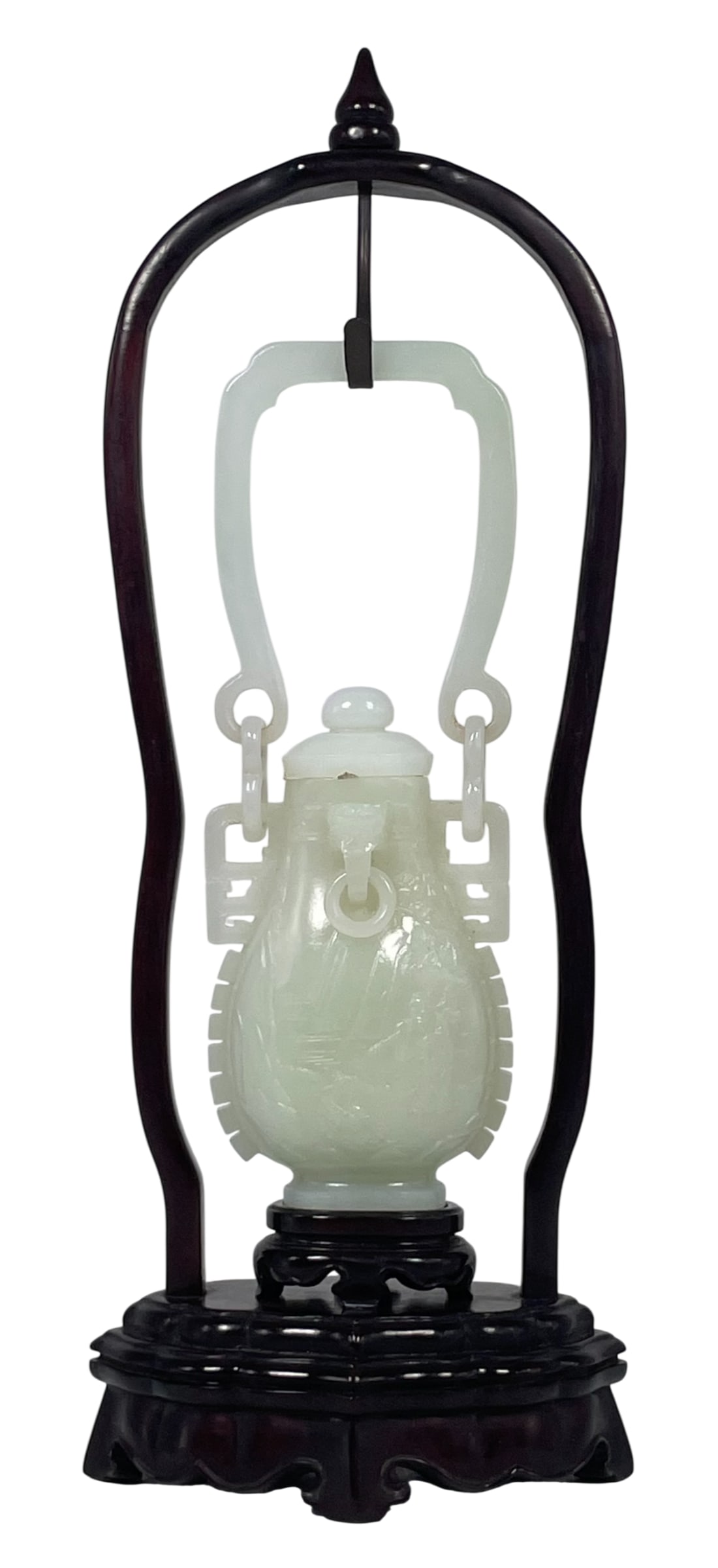 A Chinese Carved White Jade Vase and Cover: Mounted on a wood stand. The vase measures 8.1/4 in. high, 3 in. wide with extended handle; 13.1/2 in. high, 5 in. wide overall including the stand.