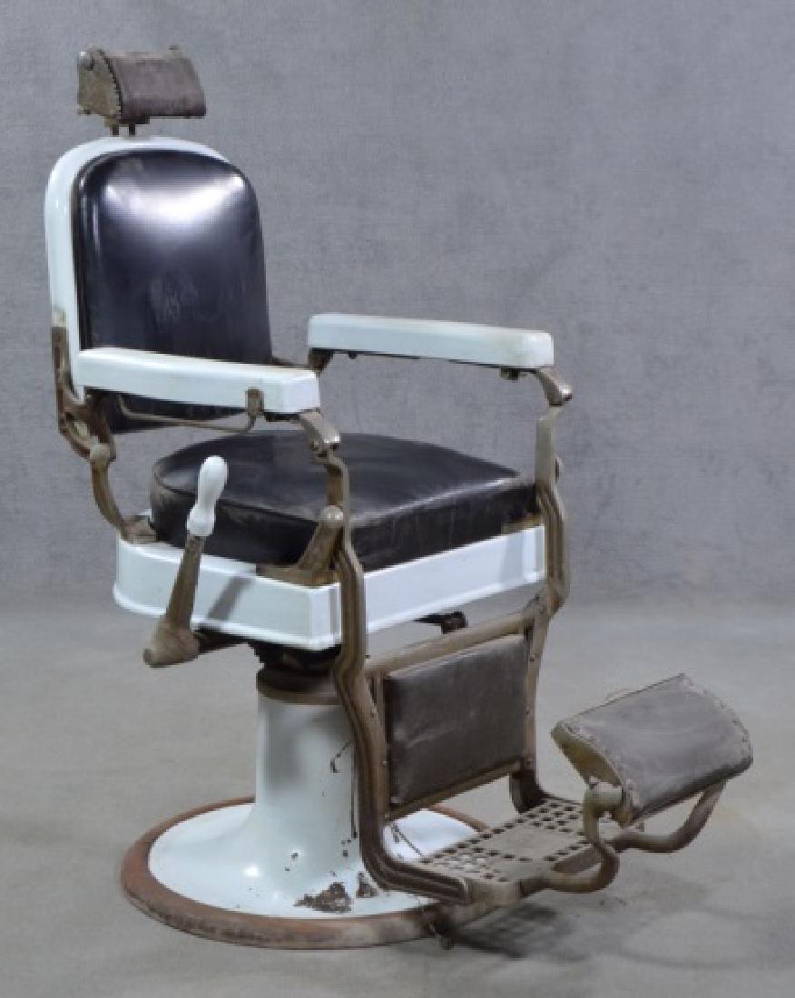 White Enamel Ceramic Barber Chair: Mid 20th century. By Koken. Black leather seat on metal white enamel base and frame. Headrest has interesting engraving and punch motif. Reclining lever on proper right side. Metal footrest marked "Ko