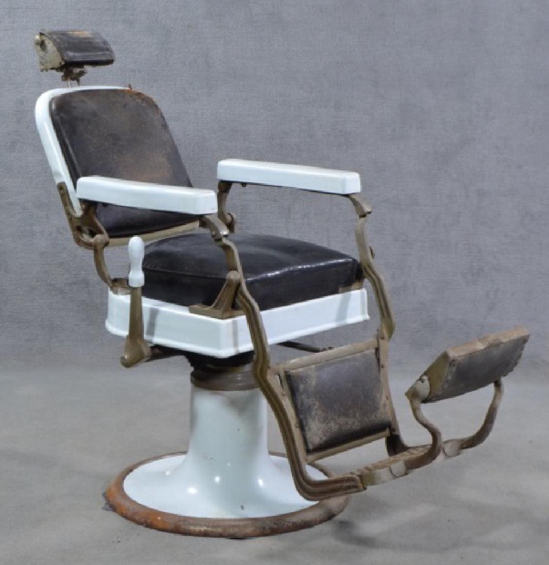 White Enamel Ceramic Barber Chair: Mid 20th century. By Koken. Black leather seat on metal white enamel base and frame. Headrest has interesting engraving and punch motif. Reclining lever on proper right side. Metal footrest marked "Ko