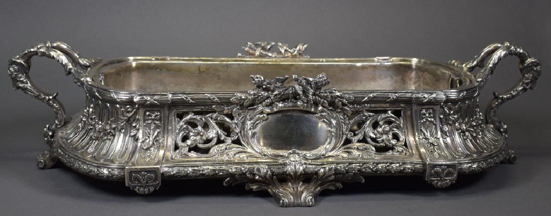 Antique Silverplate Table Centerpiece: Ornate decoration consisting of foliage, birds, musical instruments, and with rams head handles. Removeable silverplate liner. 4" H x 19" W x 9 1/4" D. Good condition.