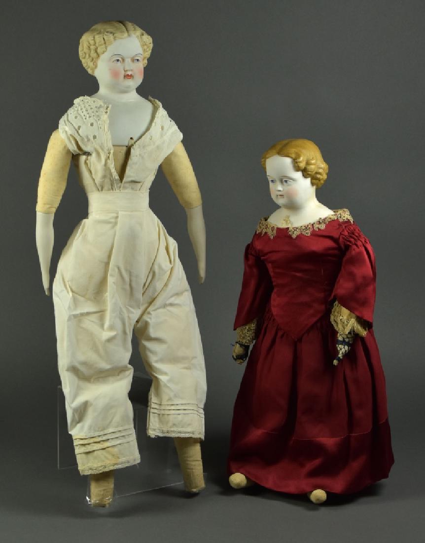 Two German Parian Dolls: One is 24"H, blonde hair bisque shoulderhead. Blue painted eyes, bisque arms, ( no feet ). Antique underwear. Second is 21"H, bisque shoulderhead with painted blue eyes, brown hair, kid arms with clot