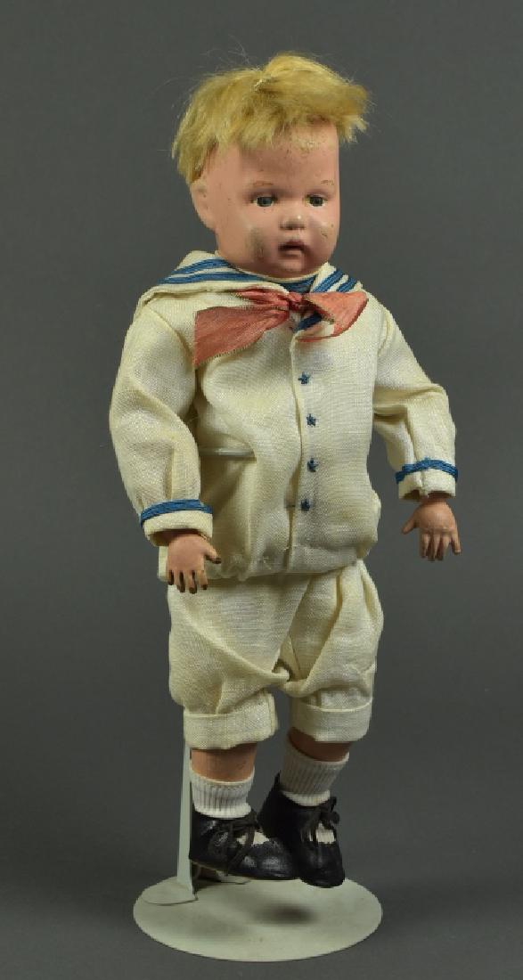 American Schoenhut Boy: 14". Blue painted eyes, blonde mohair wig. Painted brows and mouth. Stamped back of head. Dressed in antique sailor suit. Some light paint touch ups on face. Left hand replaced.