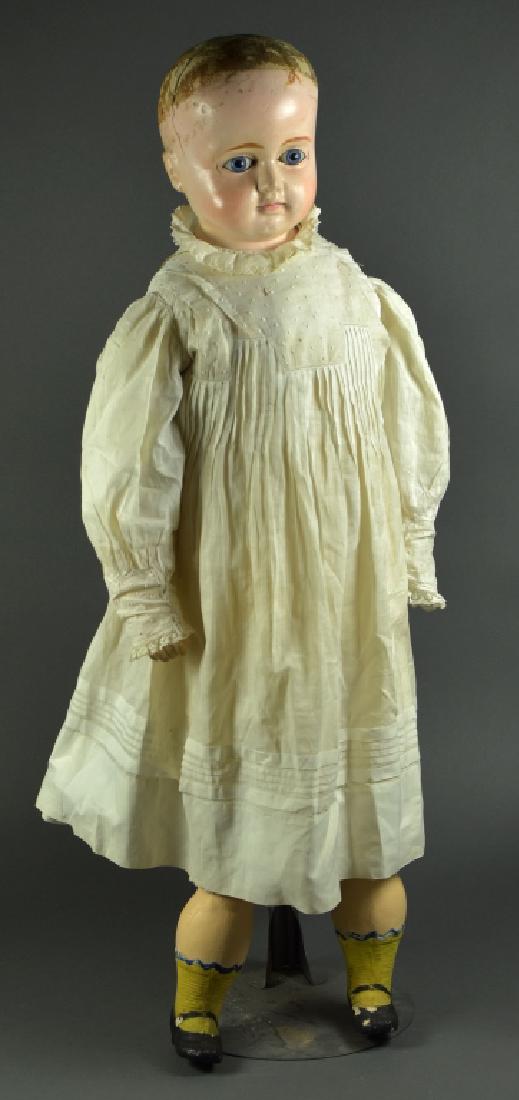 German Papier Mache: Shoulderhead with blue paperweight eyes, cloth body, and composition lower limbs. Painted shoes and socks. Dressed in antique white clothing.