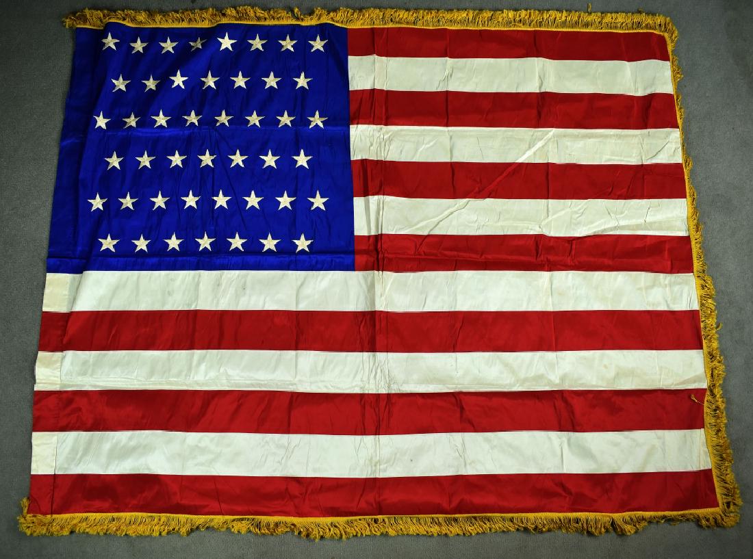 US 45 Star Flag with Yellow Cloth Fringe Satin US 45: Satin US 45 star flag with yellow cloth fringe. Has leather tabs at top and bottom of hoist side. Minor staining throughout otherwise in excellent condition. Aprox 52"T X 68"W