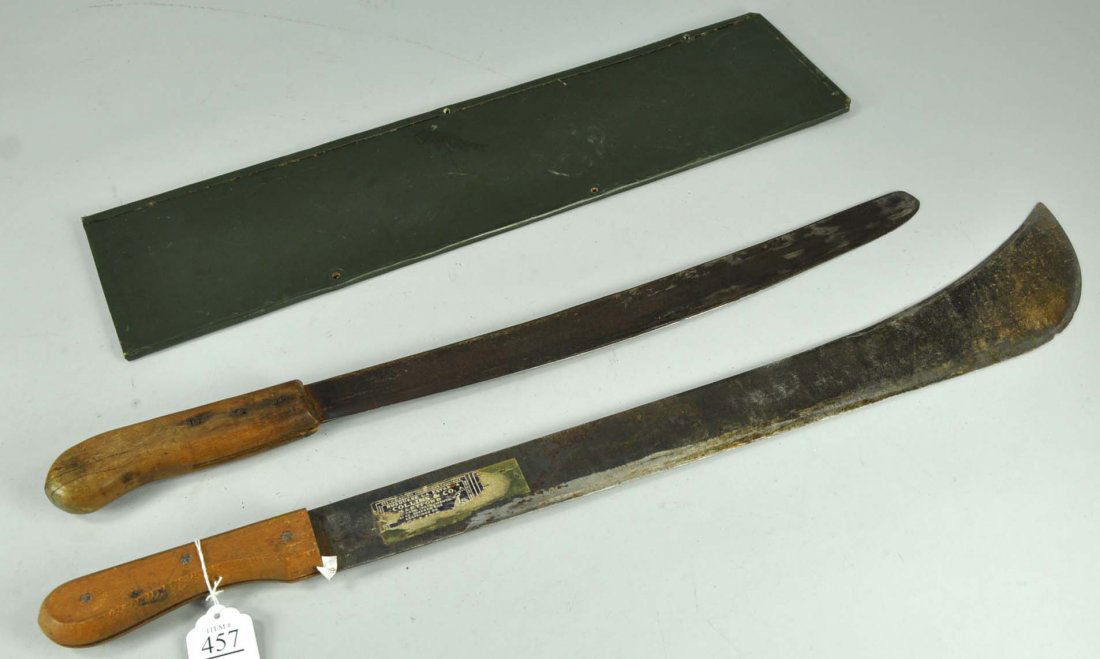 Two Machetes in Scabbard: "Village Blacksmith, Watertown, Wis."; has been well-used; handle may be replacement; 18" blade, 24 1/2" overall. And, "Legitimus, Collins & Co."; retains partial paper label on blade; 2 1/2" blade, 2