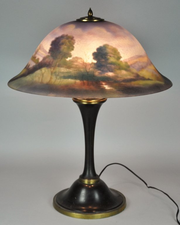 Art Glass Table Lamp: Pairpoint reverse painted shade. Signed, "G. Morely," on shade with mountainous landscape and lake design. In bell form shape and with chipped ice exterior. Slight chip on rim of shade. On associated 