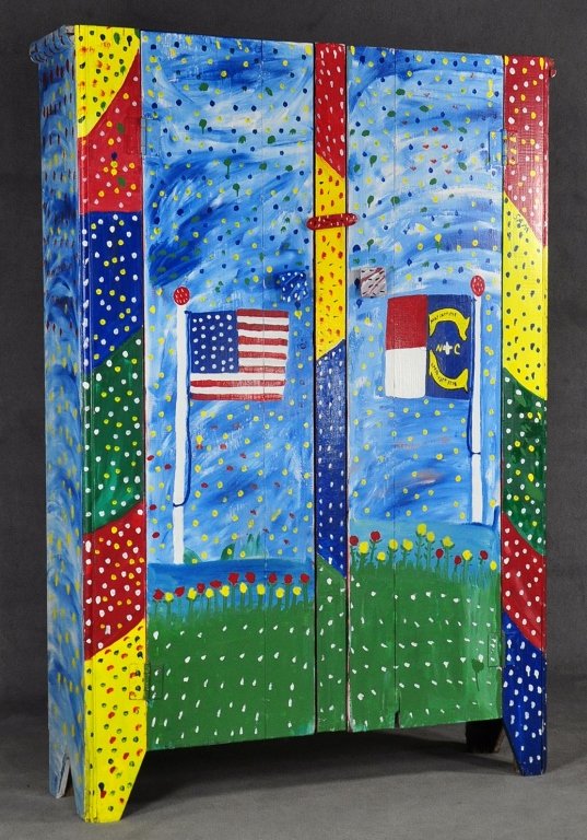 Sam McMillan Cupboard: American - N.C., born 1926. Also known as "Sam the Dot Man." With five shelves. Painted inside and out. Exterior with folky landscape, U.S. flag and N.C. flag. Showing dates of the Halifax Resolves an