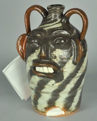 North Carolina Face Jug by Walter Fleming: Grey and white swirl glaze with brown handles and ears. Saplling to base - 2 1/2" x 2" on side and 1" x 2" on front. 10" H. overall.