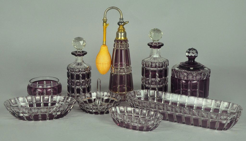 Amethyst Cut-to-Clear Glass Dresser Set: Early 20th century. Including atomizer, 8 1/18" H.; two perfume bottles; a lidded canister; a small canister lacking lid; three elongated trays, 4 1/4" to 9" L; and a ring holder (having factory polis