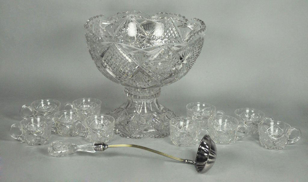 Cut Glass Punch Bowl on Stand: Hobstar, hobnail, and fan cut decoration. Some rim chips. 11" H. x 12 1/2" Dia. With silverplate ladle with crystal handle and 10 unmatched cups.