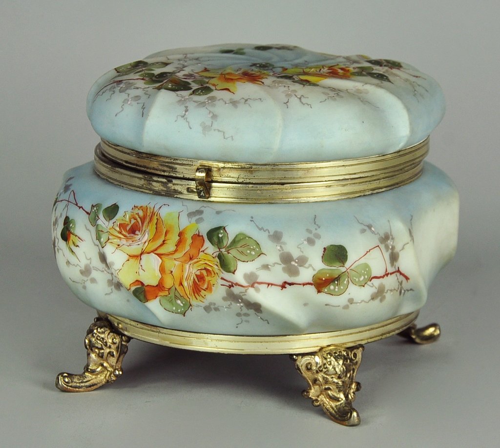 Wave Crest Jewelry Casket: By C.F. Monroe Company, 1892-1916. Interior fitted with gold colored cloth liner. Blue swirl design. Sits on metal base with four ormolu feet. Hinged lid. Decorated with yellow roses and green leafy t