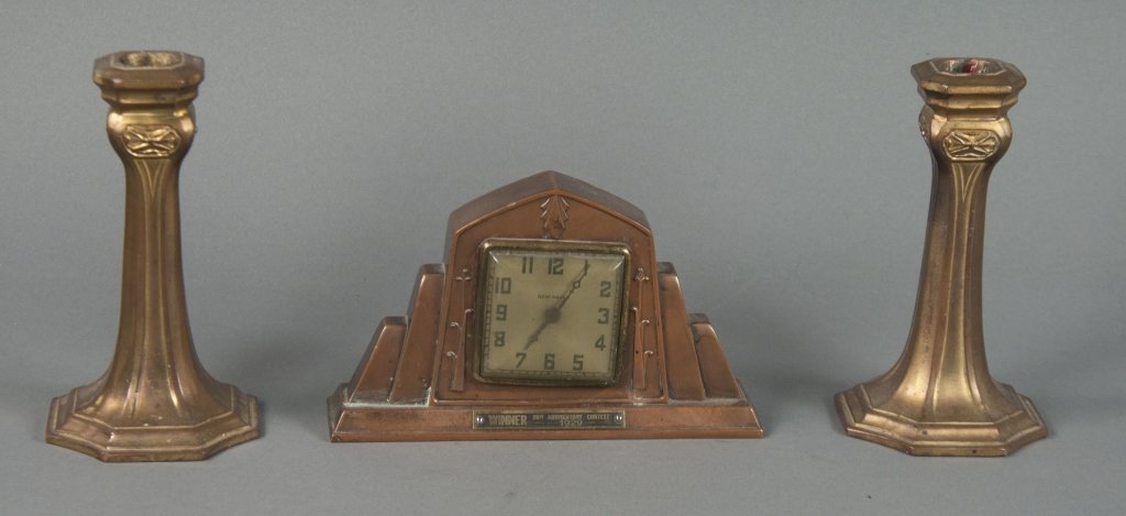 1929 Art Deco Petite Garniture Set: Spelter clock and candlesticks with bronze patina. Clock is by New Haven. Plaque on front reads "Winner 20th Anniversary Contest/1929." Clock is 4 1/4" x 7 1/8" x 1 3/4". Running condition unknown. Ca