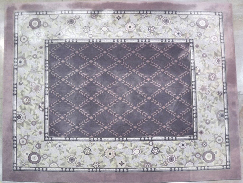 Edward Fields Large Area Rug: In moss green, mauve, and shades or purple. With mauve border surrounding second border with pastel, stylized blooms and leaves, around central panel with diaper pattern on dusty purple ground. 16' x