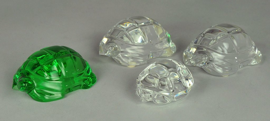 Group of Four Art Glass Turtles: Including three larger turtles (two colorless and one transparent green glass) with "Baccarat France" mark, each 4" L.; and smaller turtle signed, "Steuben," 2 3/4" L.