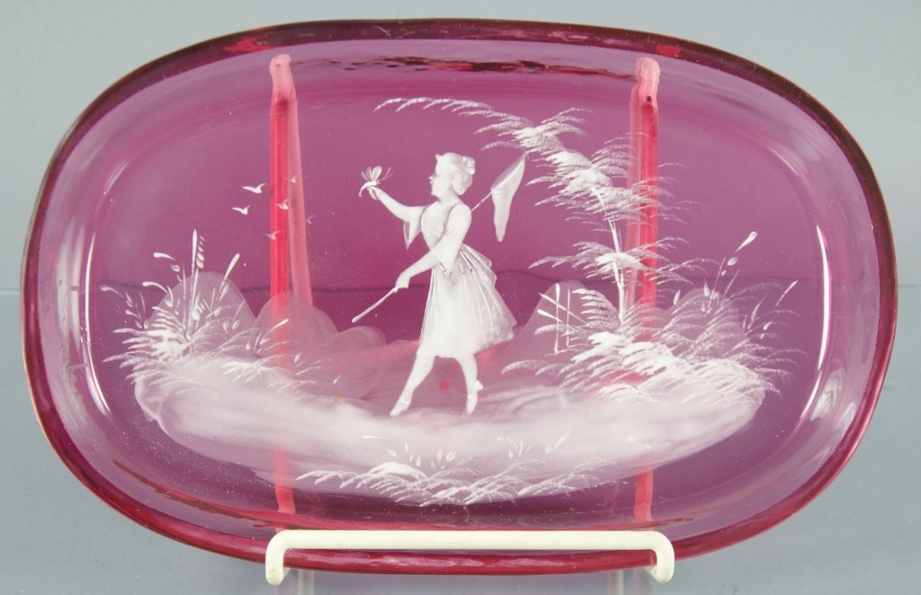 Mary Gregory Cranberry Dresser Tray: Decorated in enamel with woman carrying a butterfly net and a butterfly perched on her hand. Oval shaped, 1" x 7" x 10 3/4".