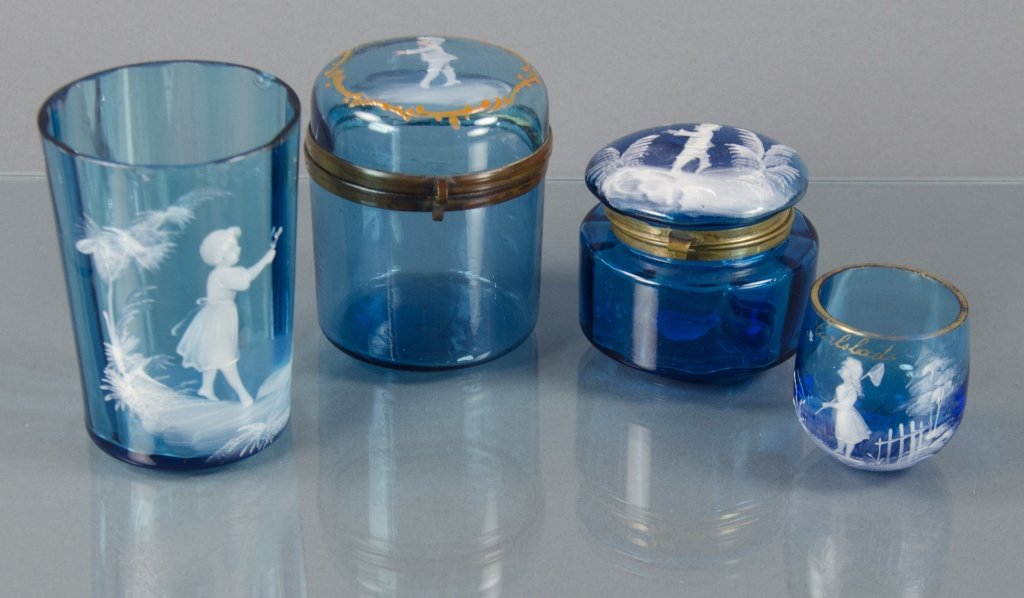 Four Blue Mary Gregory Glass Items: Including two dresser jars, 3 1/2" and 2 3/4" H.; one shot glass, 1 3/4" H.; and one tumbler 3 3/4" H. All decorated with white enamel figures of children at play. Tumbler and small dresser jar with i