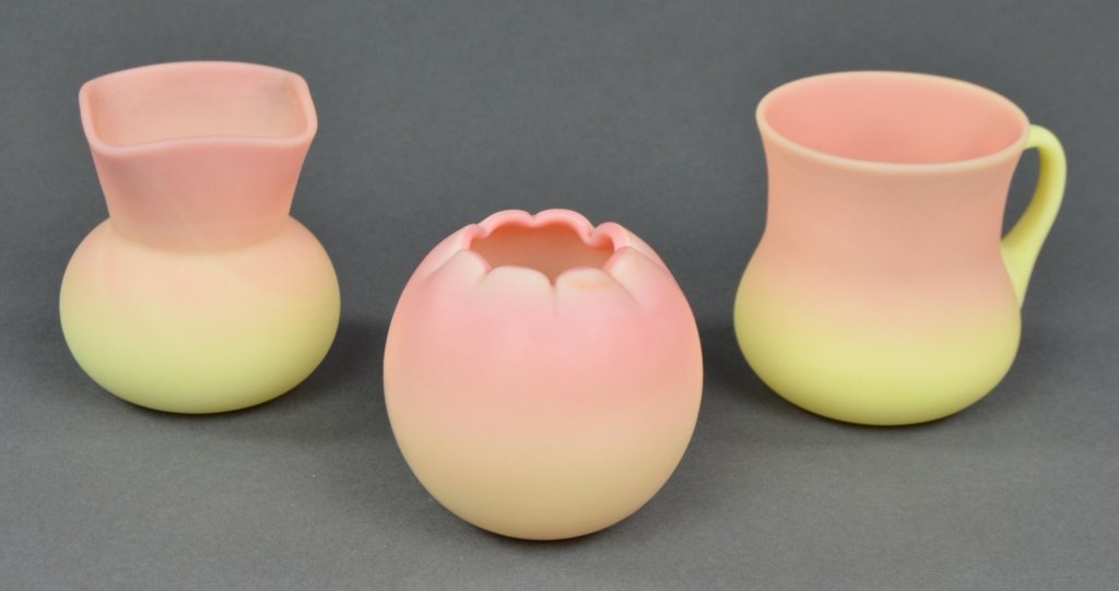 Three Small Pieces Burmese Glass by Mt. Washington: Includes one bowl, 2 1/2" H.; square-rimmed toothpick holder, 2 3/4" H.; and one cup with applied handle, 2 3/4" H. All three glow under ultraviolet light.