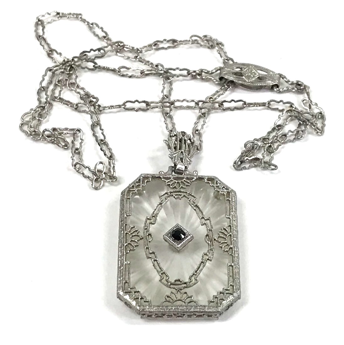 Art deco Camphor Glass Silver Lavalier Necklace: Antique art deco jeweled black crystal camphor glass silvertone metal pendant wavy chain strap lavalier necklace. Filigree clasp. The Pendant measures 1 3/8 x 3/4 inches bail included. The chain measu
