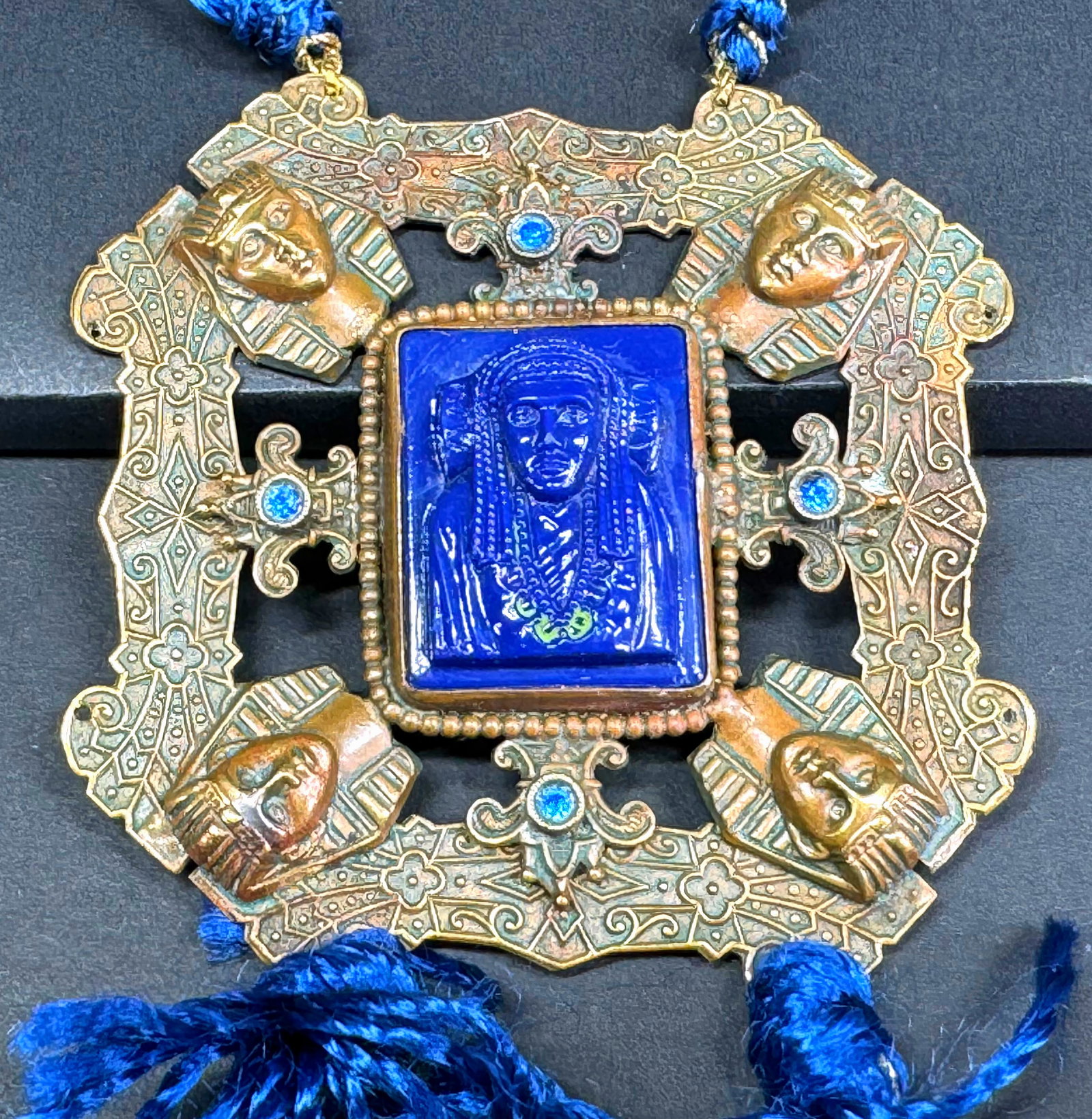 intage Egyptian Revival Neiger Bros lapis glass rhinestones goldtone medallion necklace: Vintage Egyptian Revival Neiger Bros lapis glass rhinestones goldtone metal medallion with straps & tassels necklace. Hand knotted faceted blue crystals & threads strap and tassels. The necklace is vi