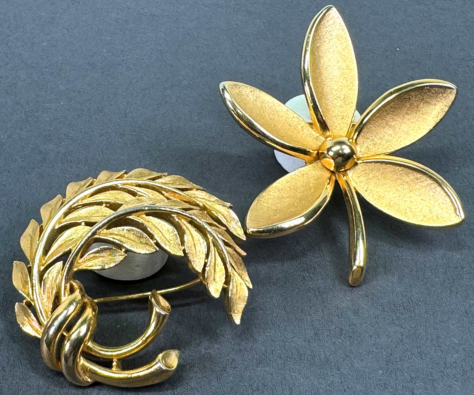 Vintage Crown Trifari goldtone metal flower & feathers pin brooches.: Vintage Crown Trifari goldtone metal flower & feathers pin brooches. Both are marked . For measures please refer to the picture taken with a measuring tape. Weight: 50 Grams. This is a NO RESERVE AUCT