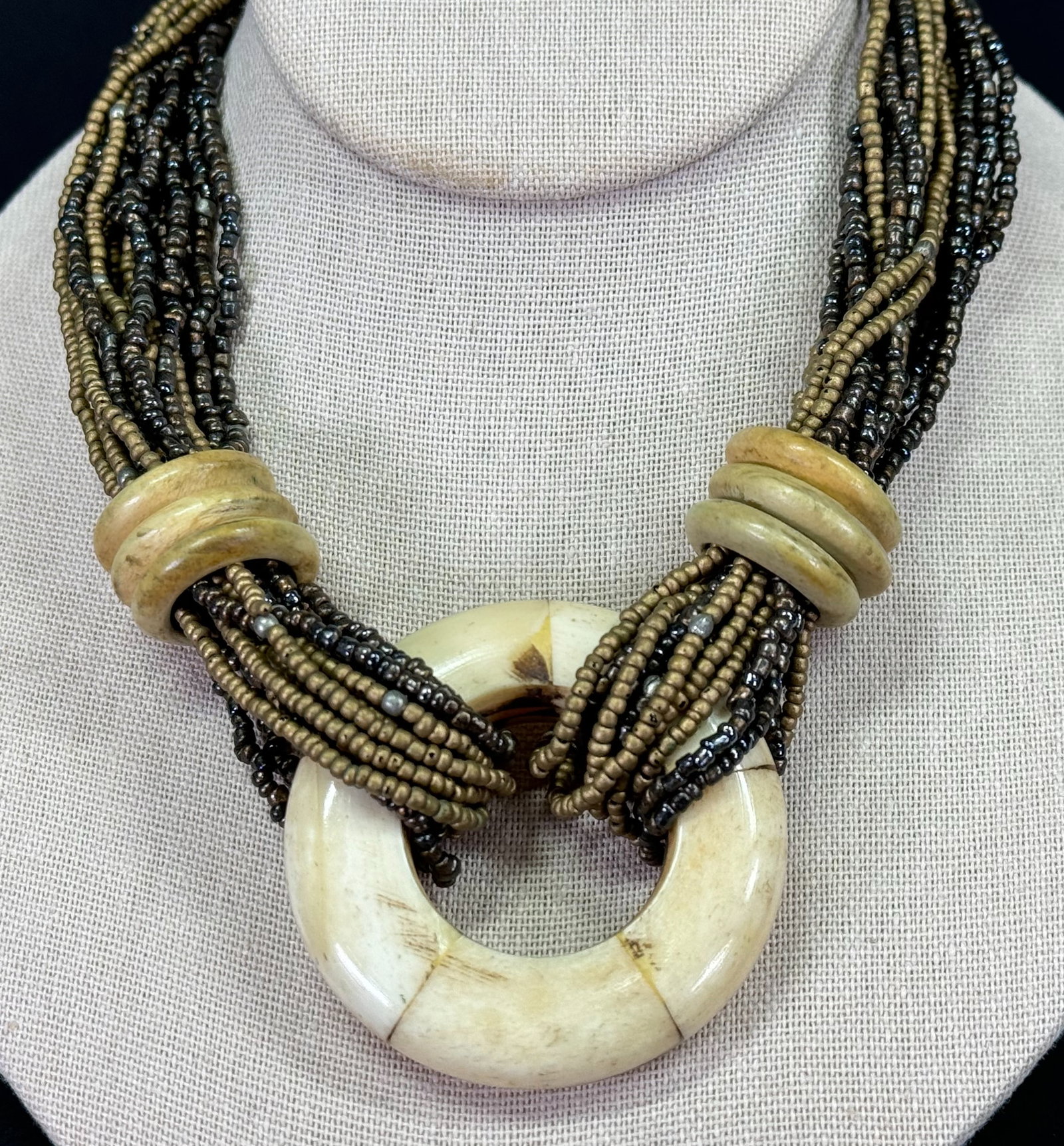 Vintage marquetry bone medallion and rings multi strand glass beaded necklace.: Vintage marquetry bone medallion and rings multi strand glass beaded necklace. Unmarked. Silvertone metal clasp. For measures please refer to the pictures taken with a measuring tape. Weight: 130 Gram