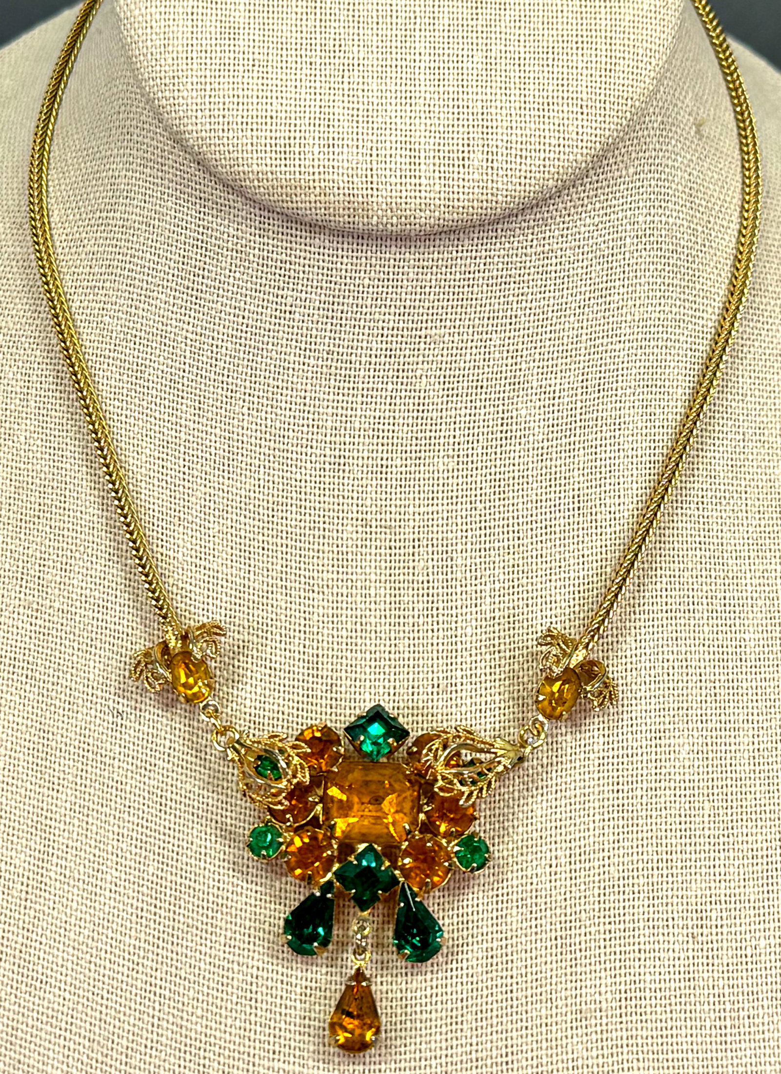 Vintage Juliana Style crystals medallion with drop dangle goldtone metal necklace: Vintage Juliana Style golden & green crystals medallion with drop dangle goldtone metal necklace. Unmarked. For measures please refer to the pictures taken with a measuring tape. Weight: 15 Grams. Thi