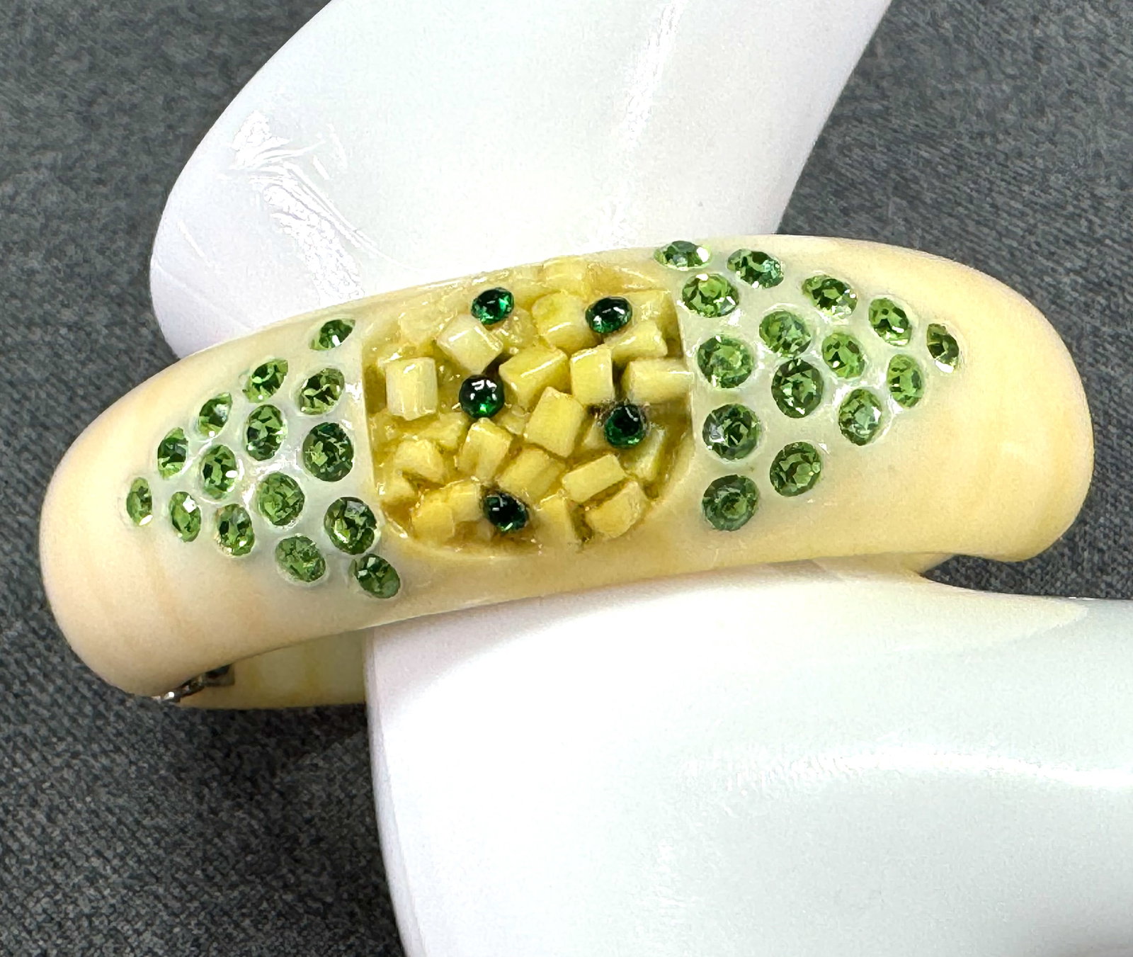 Vintage Weiss style green rhinestones & confetti yellowish accents creamy celluloid hinged bracelet: Vintage Weiss style green rhinestones & confetti yellowish accents creamy celluloid hinged bracelet. Unmarked. For measures please refer to the pictures taken with a measuring tape. Weight: 32 Grams. 