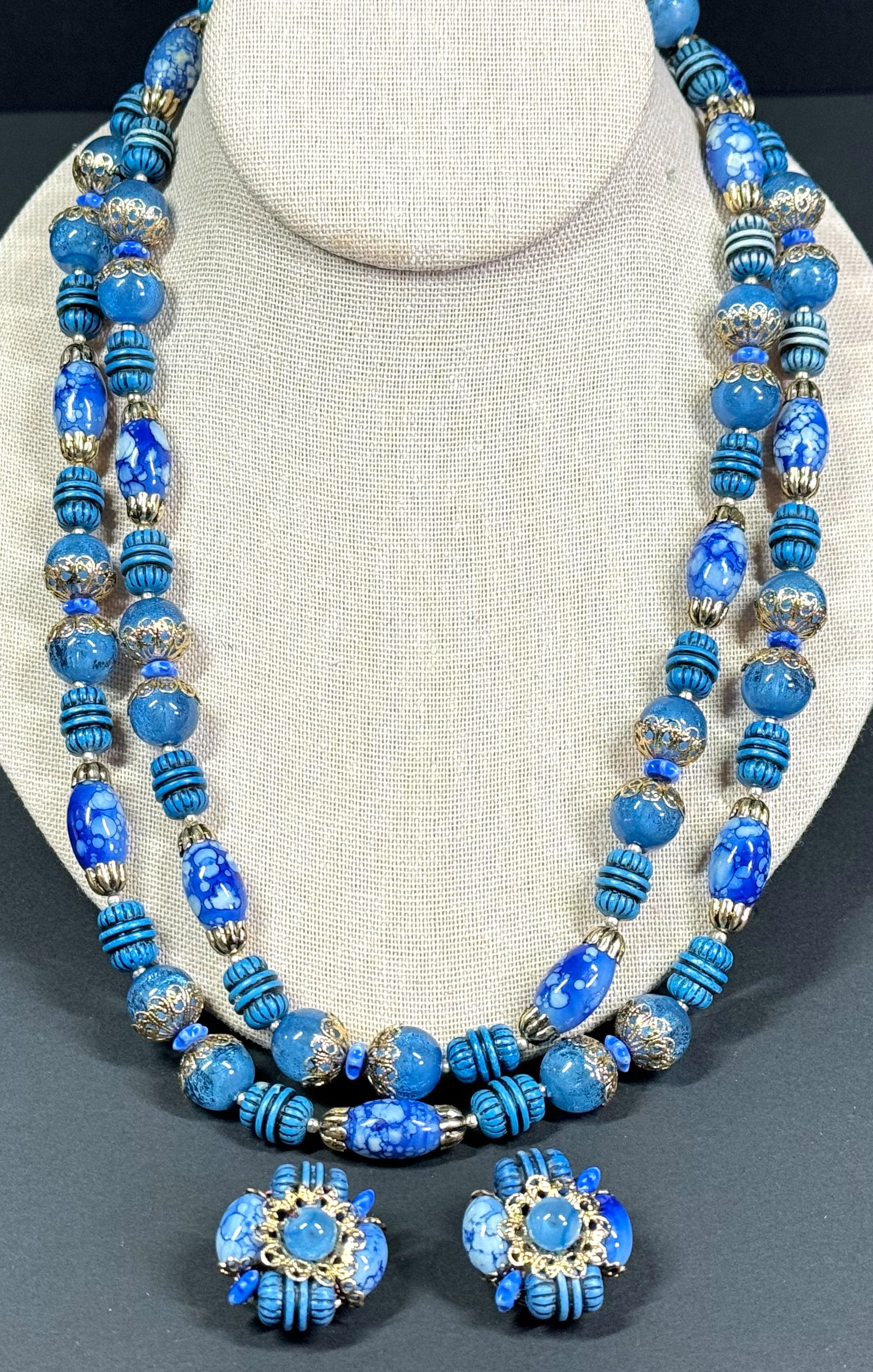 Vintage bluish plastic beads twostrands collar necklace & earrings. Hong Kong: Vintage bluish plastic beads & goldtone filigree caps 2 strands collar necklace & matching clip earrings. Marked Hong Kong. For measures please refer to the pictures takenwith a measuring tape. Weight
